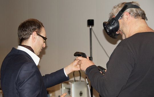 FH-Rektor Prof. (FH) Dr. Mario Döller erklärt einem Besucher die VR-Brille.