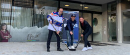 Obmann Luchner, GF-Madritsch und Rektor Döller stehen vor dem Eingangsbereich der FH Kufstein mit Eishockey-Schlägern und einem Eishockey-Spielershirt.